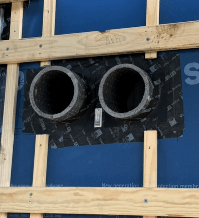 Two MVHR ducts through an external wall, sealed with Pro Clima Roflex grommets and taped back to the wall membrane with Pro Clima Tescon Extora